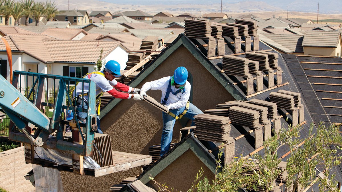 two roofing workers installing roof tile
