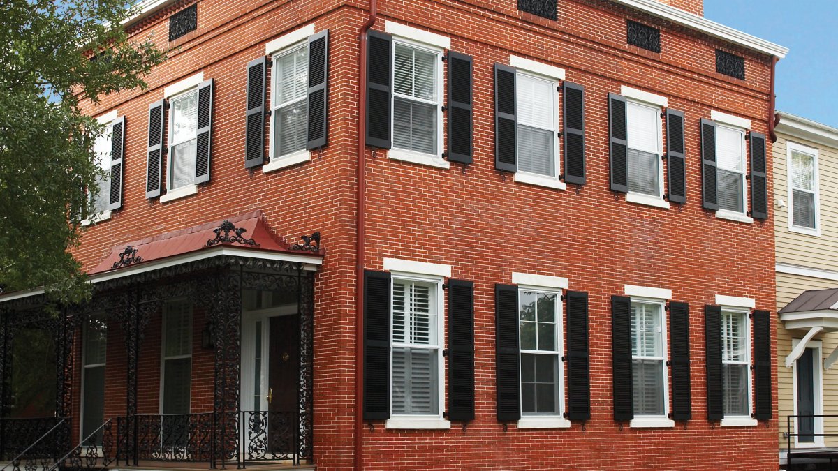 historical brick home with black shutters