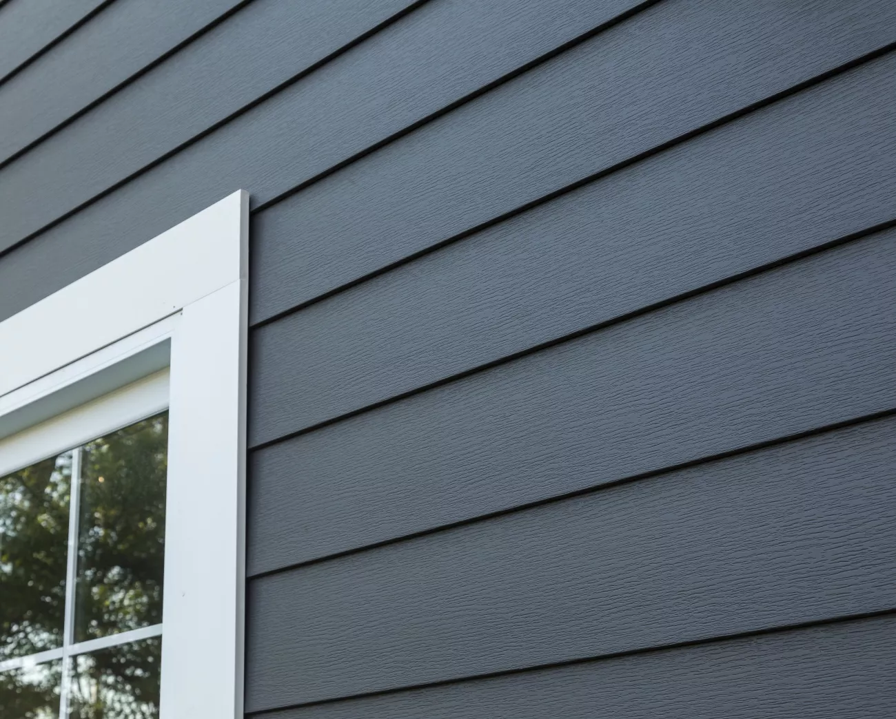 Close up of a home with dark siding and a window trim